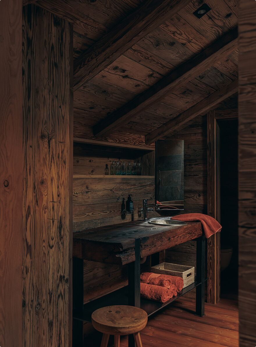 A rustic wooden interior with a wooden bench, a sink, and a shelf with bottles.