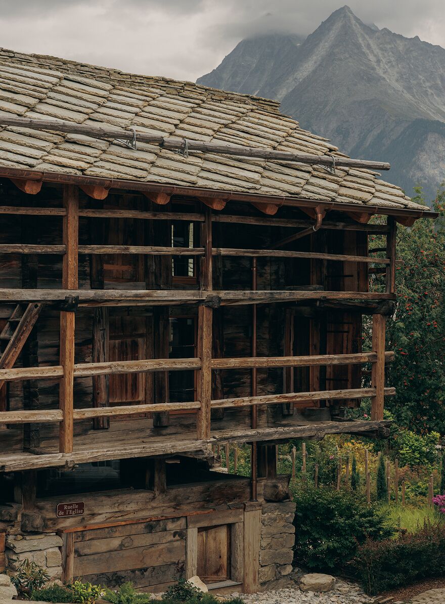 Un edificio rustico in legno con fondamenta in pietra, diversi travi in legno e un tetto spiovente.
