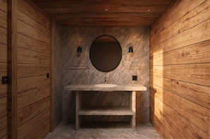 Un baño revestido de paneles de madera, con un lavamanos de mármol y un espejo redondo.