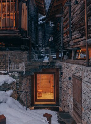Una cabaña de troncos con entrada de piedra y puerta de madera.