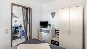 Una camera da letto con un letto, una scrivania con un computer, un armadio e una decorazione a forma di cuore sulla parete.