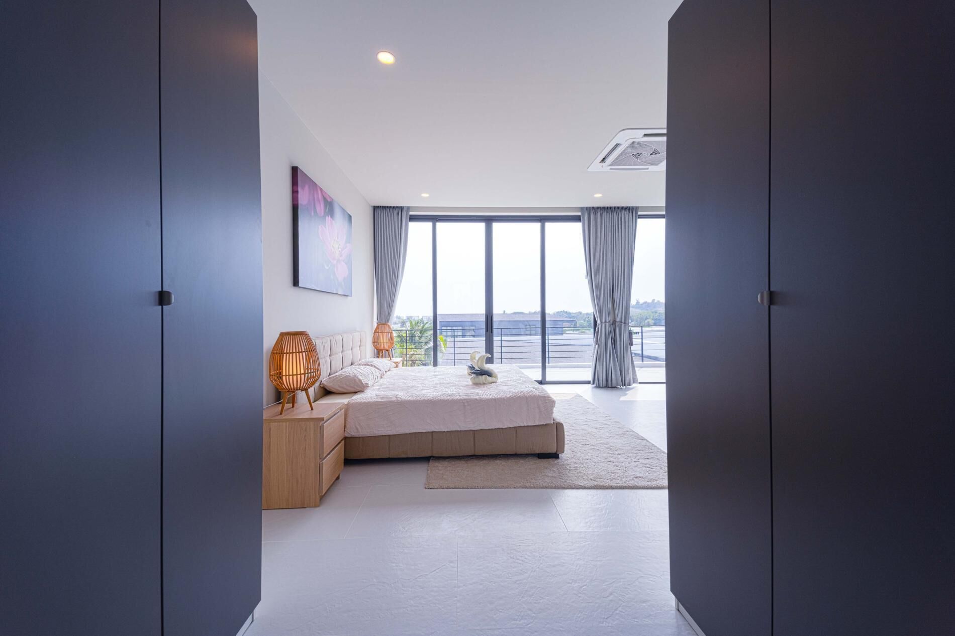 Een moderne slaapkamer met een groot bed, een nachtkastje, een lamp en uitzicht op de omgeving.