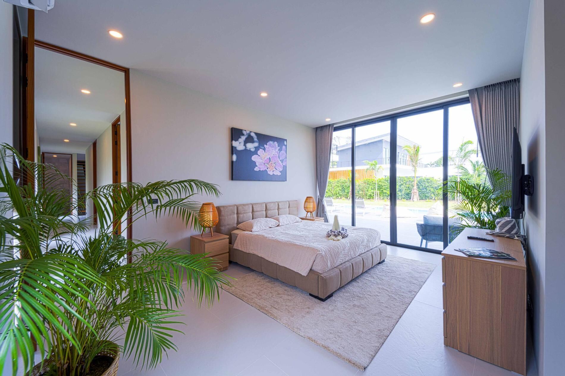 Une chambre moderne avec un grand lit, des lampes de chevet, un téléviseur à écran plat et une vue sur l’extérieur.