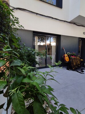 A modern building with a glass door, a guitar, and potted plants. - Bright Ground Floor with Two Patios in Nervión. Metro (Sevilla)