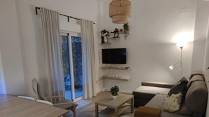 Un soggiorno moderno con tavolo da pranzo, divano, televisione e un'ampia finestra con tende.