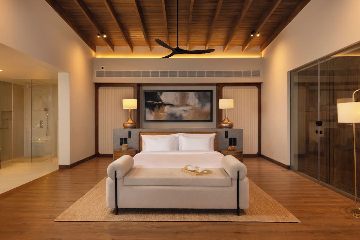 Un dormitorio moderno con una cama grande, un ventilador de techo y un cuadro grande sobre la cama.