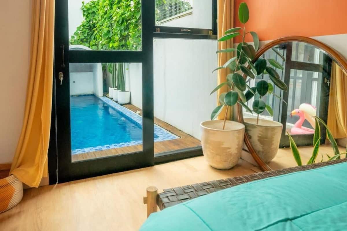 Ein Zimmer mit Blick auf einen Pool, einer Topfpflanze und einem Spiegel, der eine Flamingostatue reflektiert.