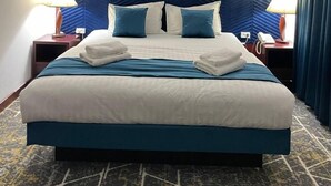 A hotel room with a large bed, a headboard with a geometric pattern, a framed picture on the wall, and a telephone on the nightstand. - Regal Garden Hotel (Samarkand)