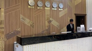 A reception desk with clocks indicating different time zones, a chandelier, and a modern design. - Regal Garden Hotel (Samarkand)