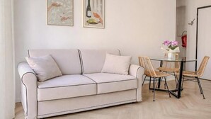 Ein modernes Wohnzimmer mit einer Couch, einem Esstisch mit Stühlen und zwei gerahmten Kunstwerken an der Wand.