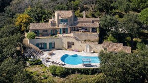 Una gran villa con piscina, varias terrazas y abundante vegetación alrededor.