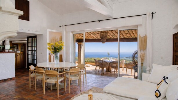 Un salón amplio con una mesa de comedor, sillas, sofá y vista al mar.