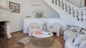 Una sala de estar con chimenea, dos sillones, una mesa de centro y una escalera.