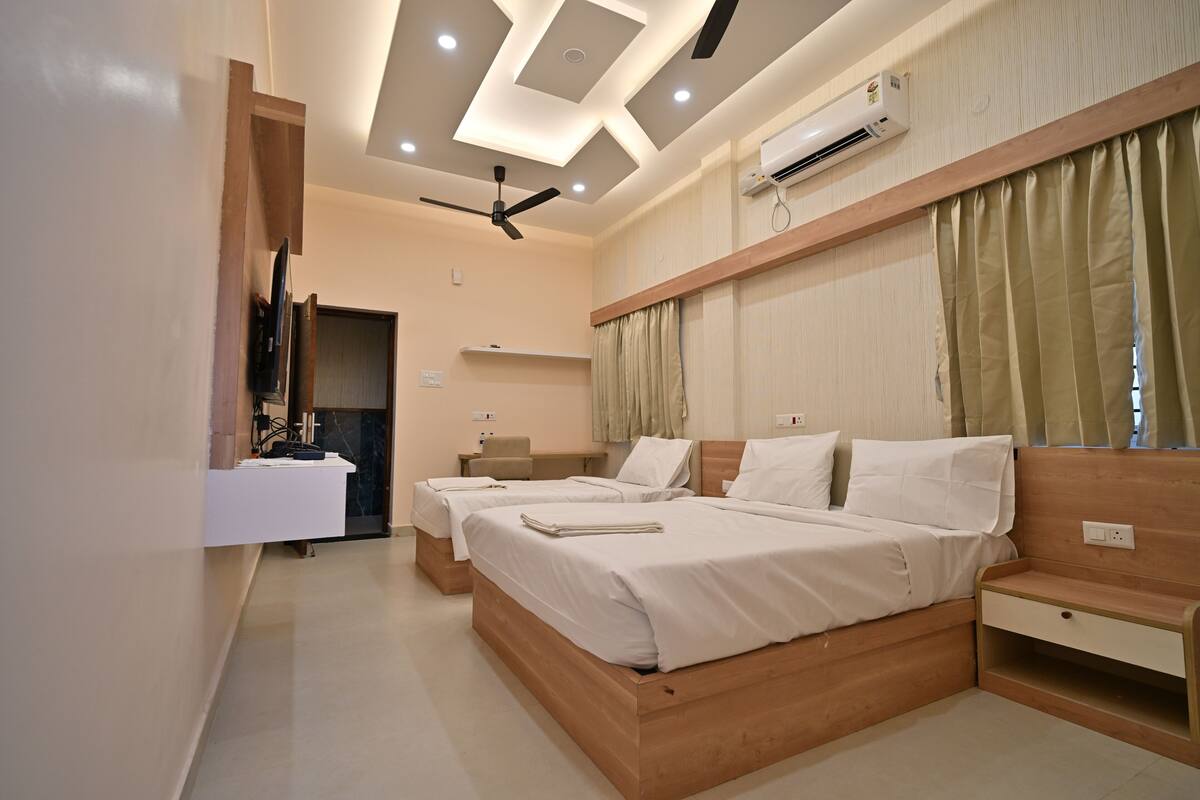 Habitación de hotel moderna con una cama de madera, mesitas de noche, un ventilador de techo y un equipo de aire acondicionado.