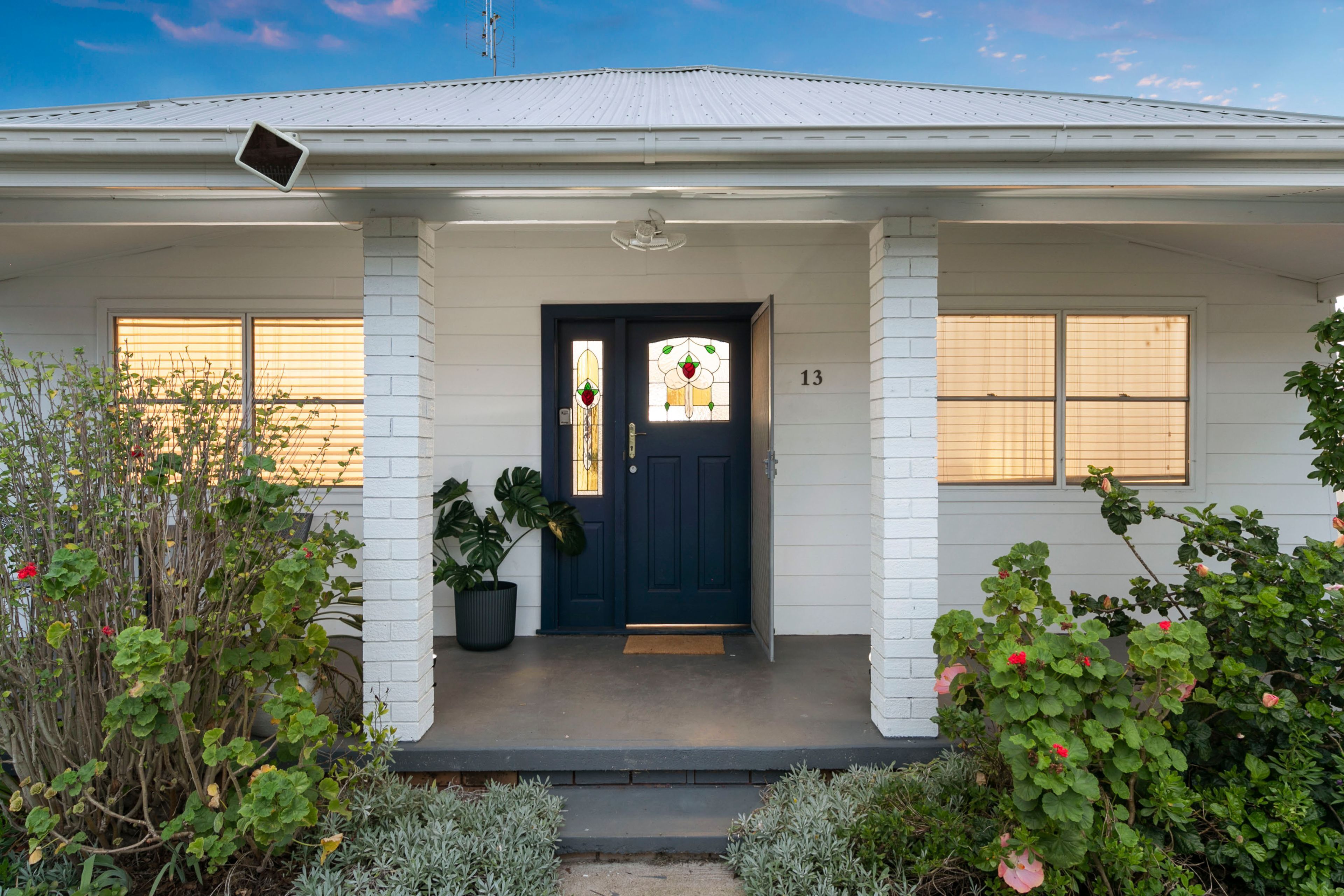 A two-story house with a dark blue front door, white brick columns, and a small porch.