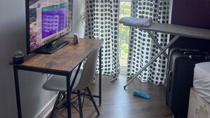 A room with a wooden desk, a computer, a chair, a bed, a suitcase, and a window with curtains. - Privet bedroom in share home (London)