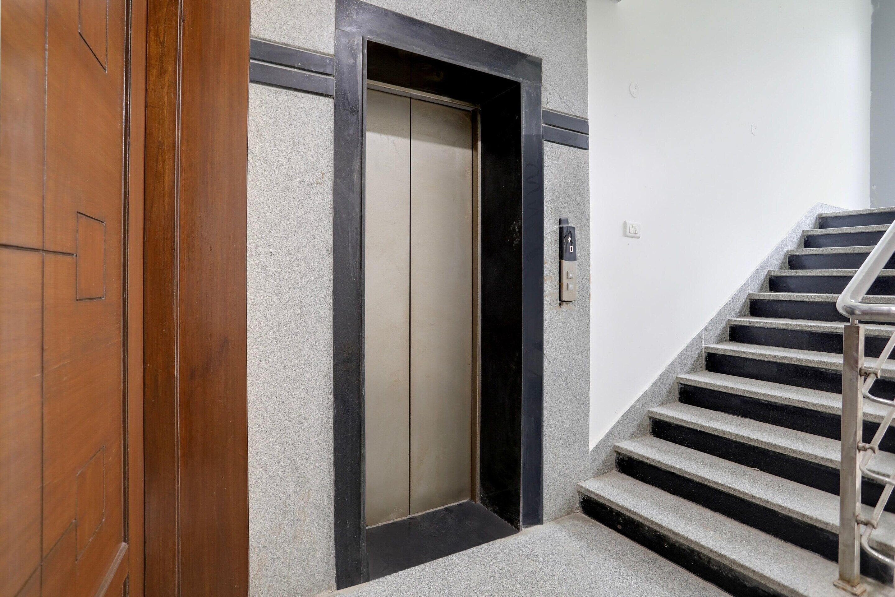 An elevator, a staircase with metal railings, and a wall with a textured surface.