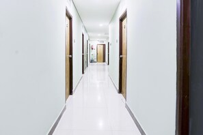 A long, narrow hallway with white walls and doors on both sides. - Deluxe With Twin Bedhotel SPG Grand (Hyderabad)