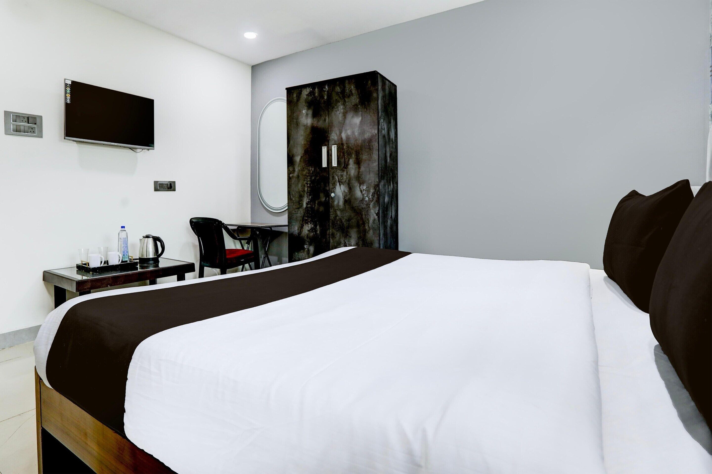 Une chambre d’hôtel avec un grand lit, un bureau avec une chaise, une télévision et une armoire.