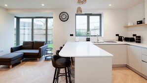 Eine moderne Küche mit Kochinsel, Barhocker, einer Couch und einem Essbereich.