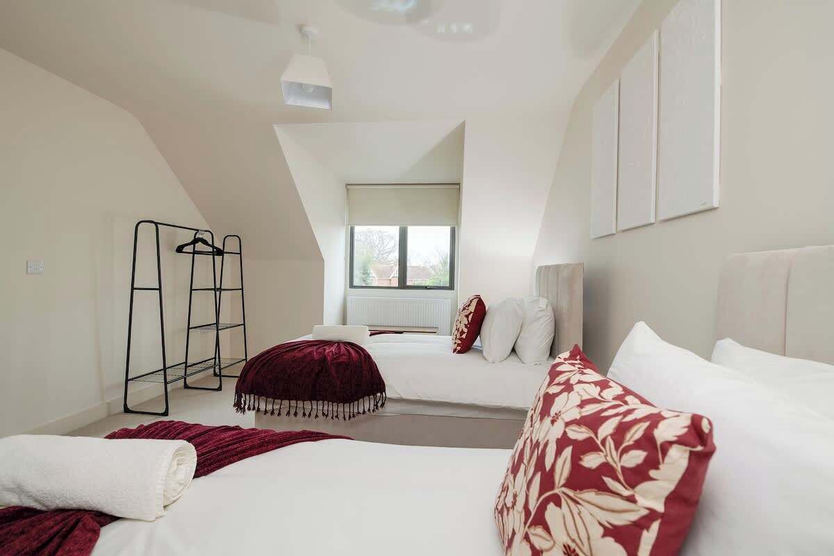 A bedroom with two beds, a window, and a radiator.