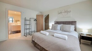 Ein Schlafzimmer mit einem großen Bett, einem Kleiderschrank, einem Spiegel und einer Tür zu einem Badezimmer.