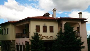 Un bâtiment à deux étages doté d’un balcon, d’une enseigne indiquant « Hôtel Zia Tizianu Kontapiki » et d’un toit recouvert de tuiles rouges.