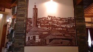 Une photographie encadrée représentant une ville avec un clocher imposant, peut-être celui d’une église, et un mur de pierre sur la gauche.