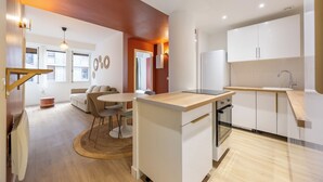 Une cuisine moderne avec des armoires blanches, un plan de travail en bois et un four encastré.