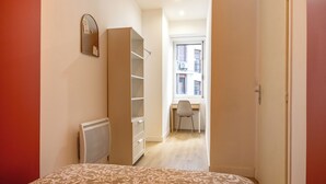 Une chambre comprenant un lit, une armoire, un radiateur et une fenêtre donnant sur un balcon.