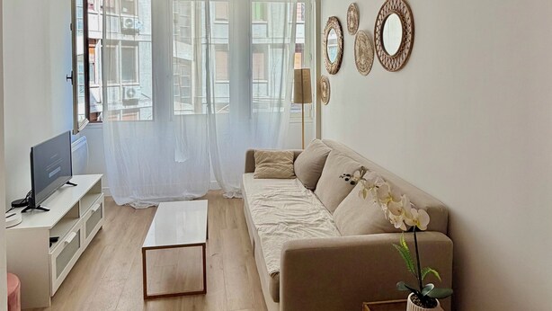 Un salon comprenant un canapé, une table basse, un téléviseur et des miroirs décoratifs.