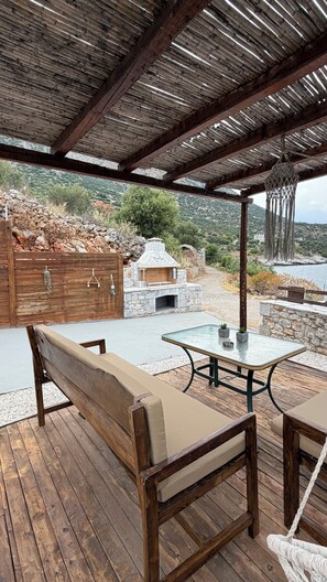 Une terrasse extérieure avec des meubles en bois, un barbecue en pierre et une vue sur un paysage montagneux.