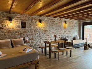 Une pièce aux murs de pierre, avec un lit, une table et des bancs.