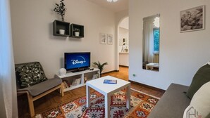 Un saló amb televisió de pantalla plana, un sofà, una taula de centre i una catifa amb dibuixos.