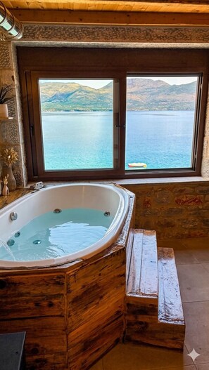 Una vasca da bagno in legno con vista su un lago e montagne.