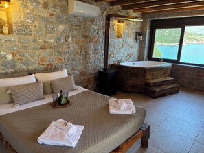 Un dormitorio con paredes de piedra, una cama, un banco de madera y una bañera.