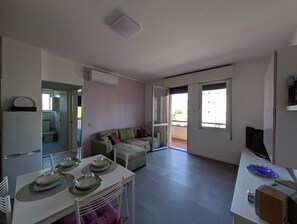 Eine moderne Küche mit Essbereich, einer Couch und einem Fernseher.