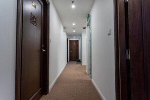 Ein Korridor mit Teppichböden, Holztüren und eingelassener Beleuchtung.