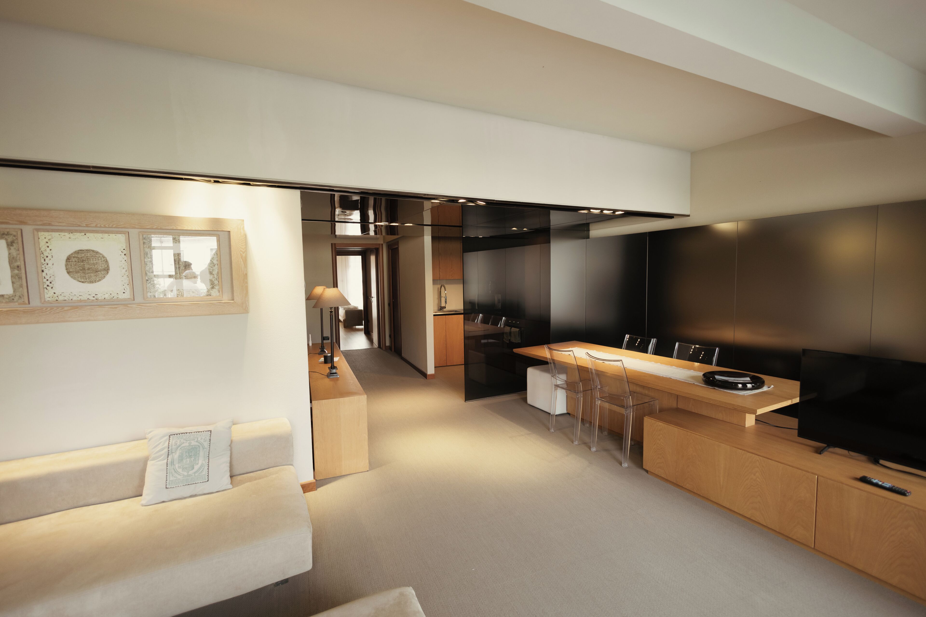 A modern kitchen with a dining area, a sofa, and a TV.