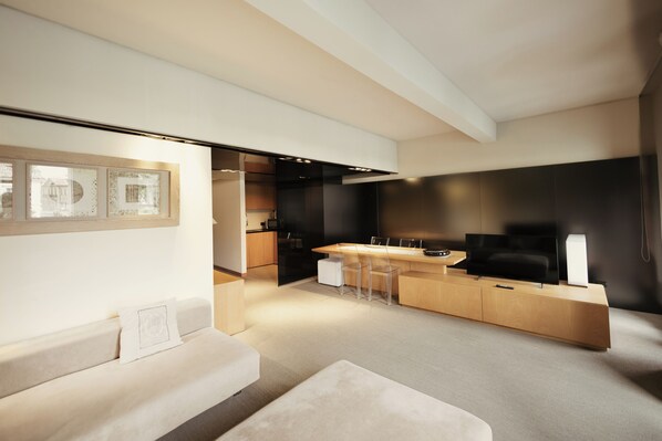 Una sala de estar moderna con sofá, una mesa de centro y una zona de cocina con mesa y sillas.