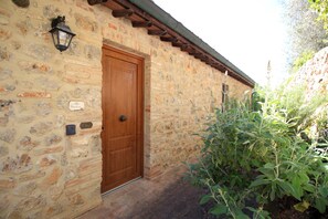 A stone building with a wooden door, a lantern, and a sign. - House in the Chianti countryside of the Sienese hills (Toscana)