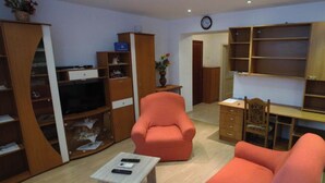 A living room with a sofa, armchair, TV, and wooden shelving. - Comfortable Apartment in the Center of Split (Split)