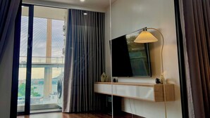 A modern hotel room with a large mirror, a flat-screen TV, and a view of a bridge. - Jade Leaves Homestay HaLong -Seaview (Hong Gai)