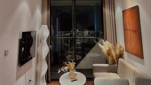A modern living room with a chandelier, a flat-screen TV, a sofa, a coffee table, and a view of the outside. - Jade Leaves Homestay HaLong -Seaview (Hong Gai)