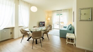 A modern living room with a glass dining table, comfortable seating, a sofa, and a small white table. - Elegant residence overlooking Porta Leoni (Verona)