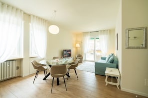 A modern living room with a glass dining table, comfortable seating, a sofa, and a small white table. - Elegant residence overlooking Porta Leoni (Verona)