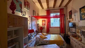 Una habitación con cama, una mesa, una silla, un armario y una ventana con cortinas.