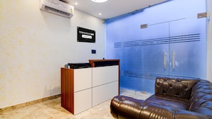 A reception area with a wooden desk, a leather couch, a blue wall, and a sign that reads 'TOWNHOUSE OAK Company Services'.
