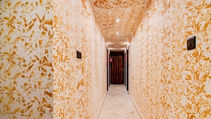 A hallway with patterned walls and a marble floor, leading to a door.