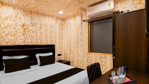 A hotel room with a bed, bedside table, and a tray with cups and a kettle.